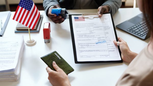 ormulario de solicitud de visa para Estados Unidos con sello de aprobación y pasaporte en mano